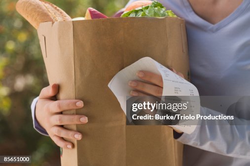 Woman holding grocery bag and receipt Woman holding grocery bag and receipt