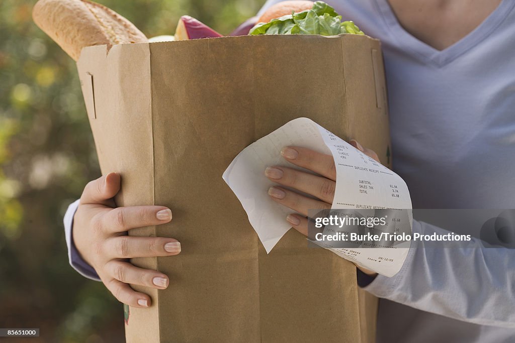 Woman holding grocery bag and receipt