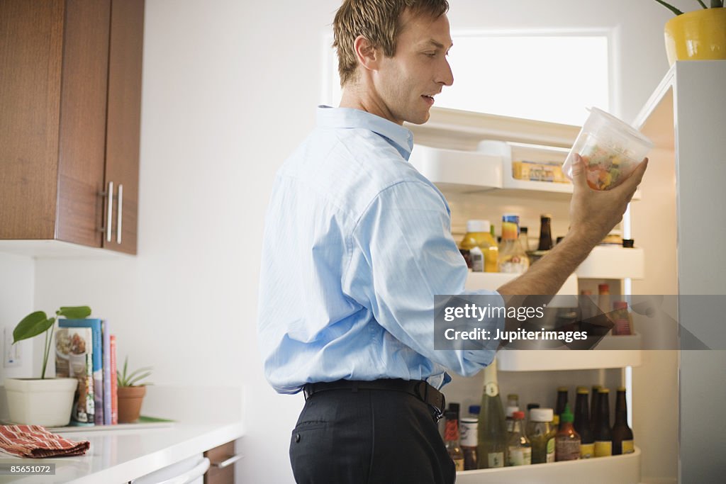 Man looking at leftovers in refrigerator