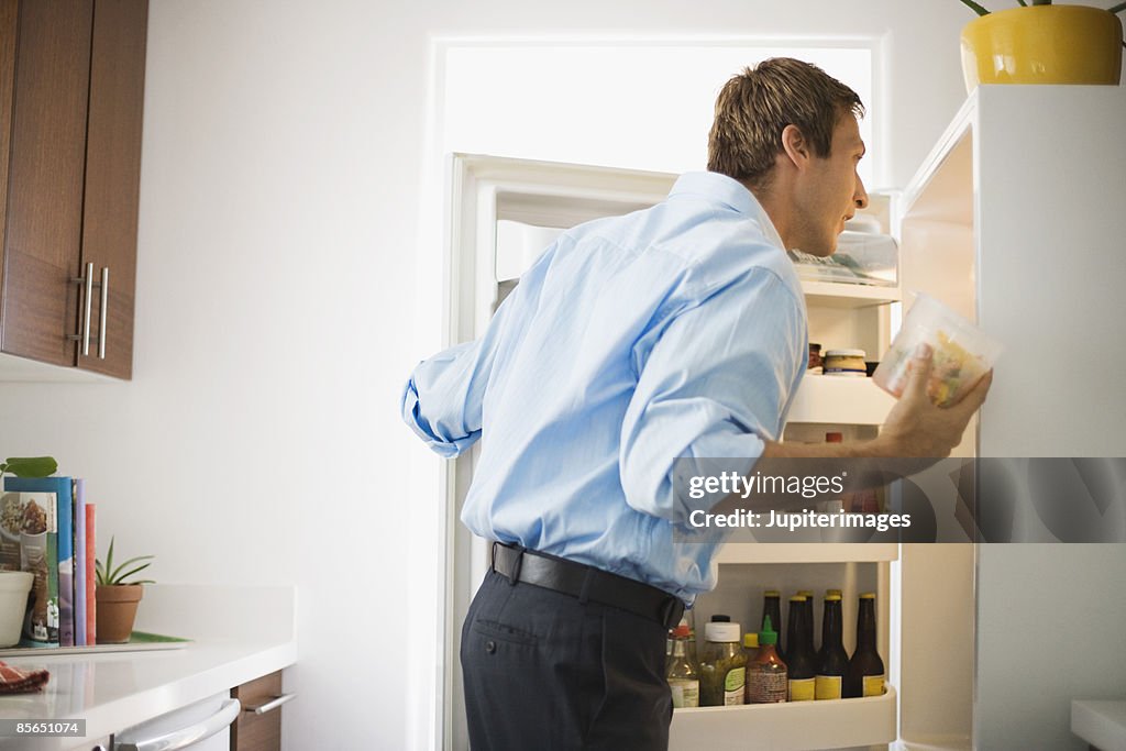 Man looking at leftovers in refrigerator