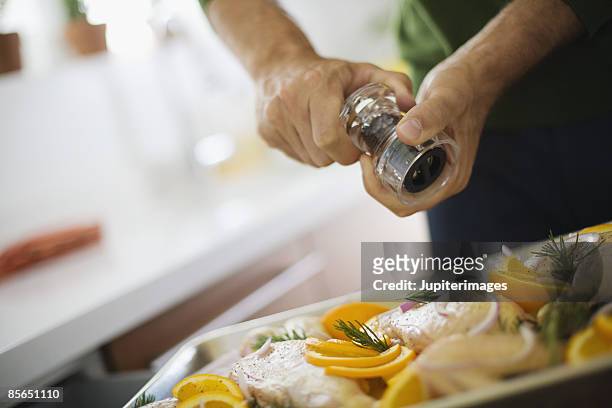 grinding pepper on rosemary chicken - grano di pepe nero foto e immagini stock