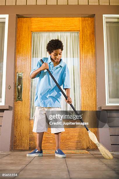 boy with broom sweeping porch - barrer fotografías e imágenes de stock