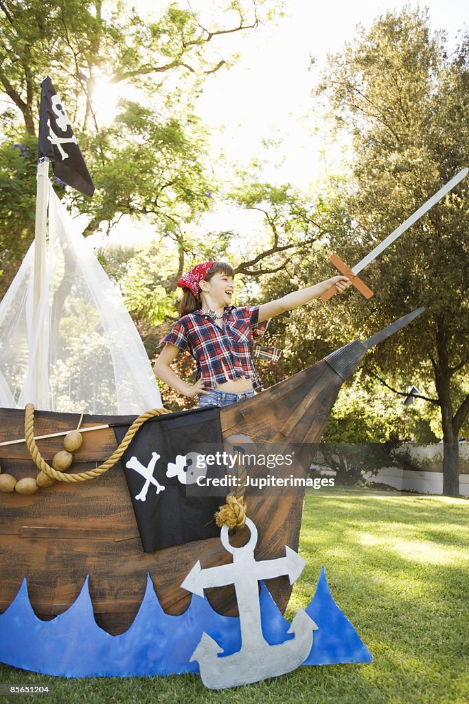 Girl in pirate costume playing in boat