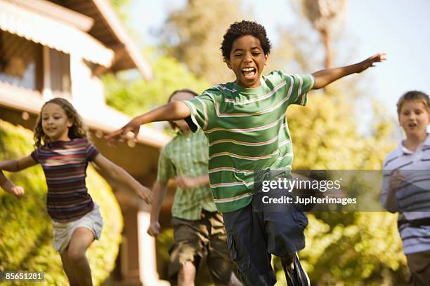 boy with friends and arms outstretched - niñez fotografías e imágenes de stock