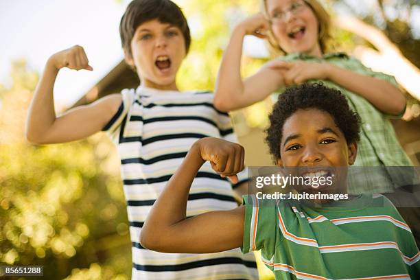 smiling boys flexing muscles - child strong stock-fotos und bilder