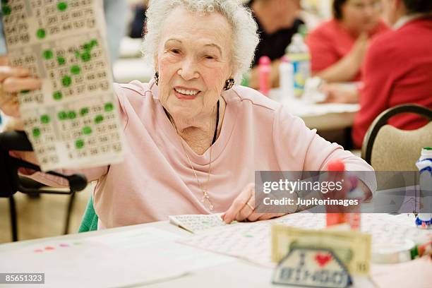 smiling woman playing bingo - bingo stock-fotos und bilder