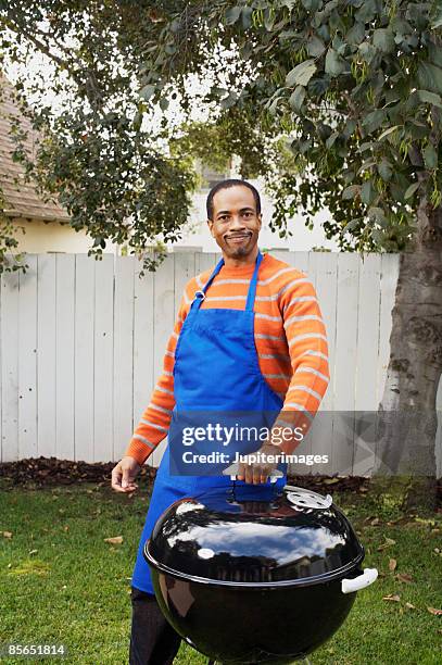 proud man putting lid on grill - bbq apron stock pictures, royalty-free photos & images