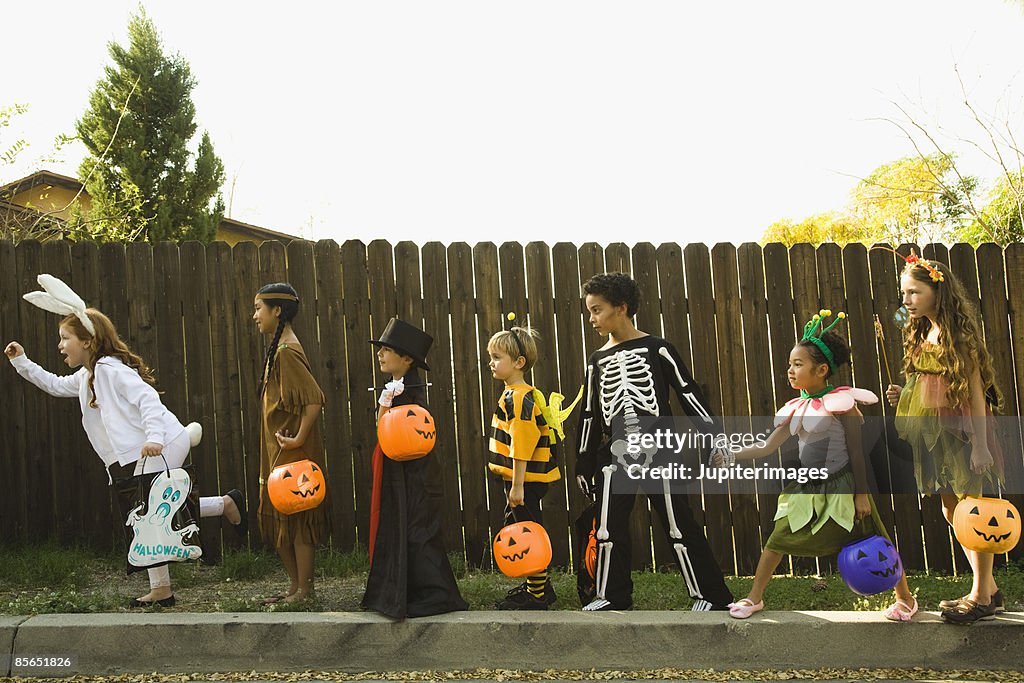 Children in Halloween costumes holding hands