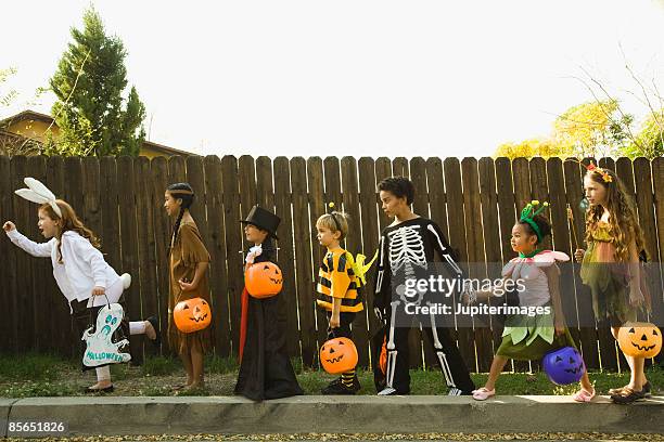 children in halloween costumes holding hands - halloween kids stockfoto's en -beelden