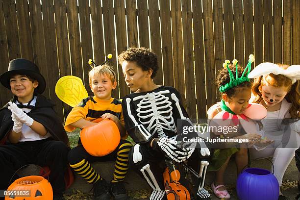 children in halloween costumes sitting on sidewalk - máscara disfarce imagens e fotografias de stock