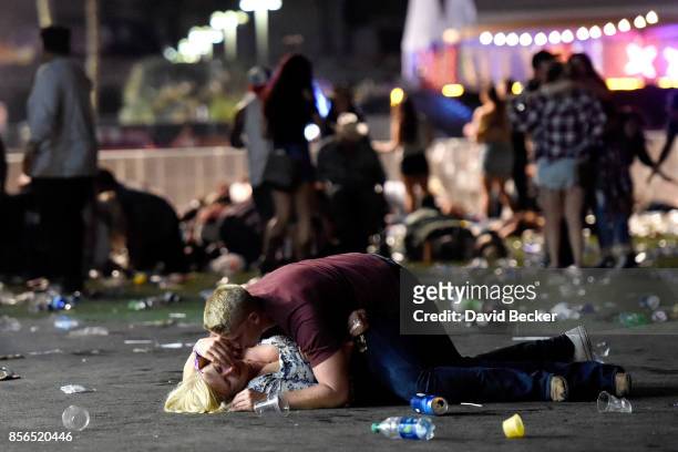 Man lays on top of a woman as others flee the Route 91 Harvest country music festival grounds after a active shooter was reported on October 1, 2017...