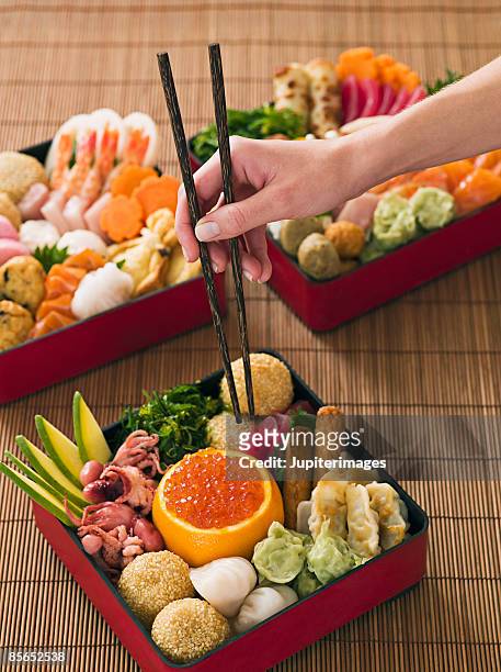 person with chopsticks and japanese new year bento box - bento imagens e fotografias de stock