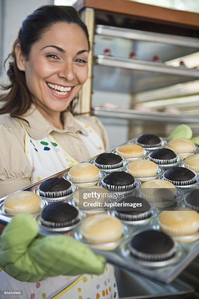 Smiling woman with tray of cupcakes