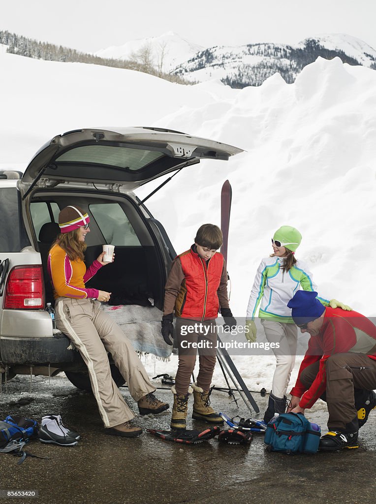 Family on snowy mountain with SUV and snowshoes