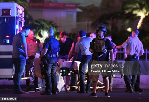 Police officers stand by as medical personnel tend to a person on Tropicana Ave. Near Las Vegas Boulevard after a mass shooting at a country music...