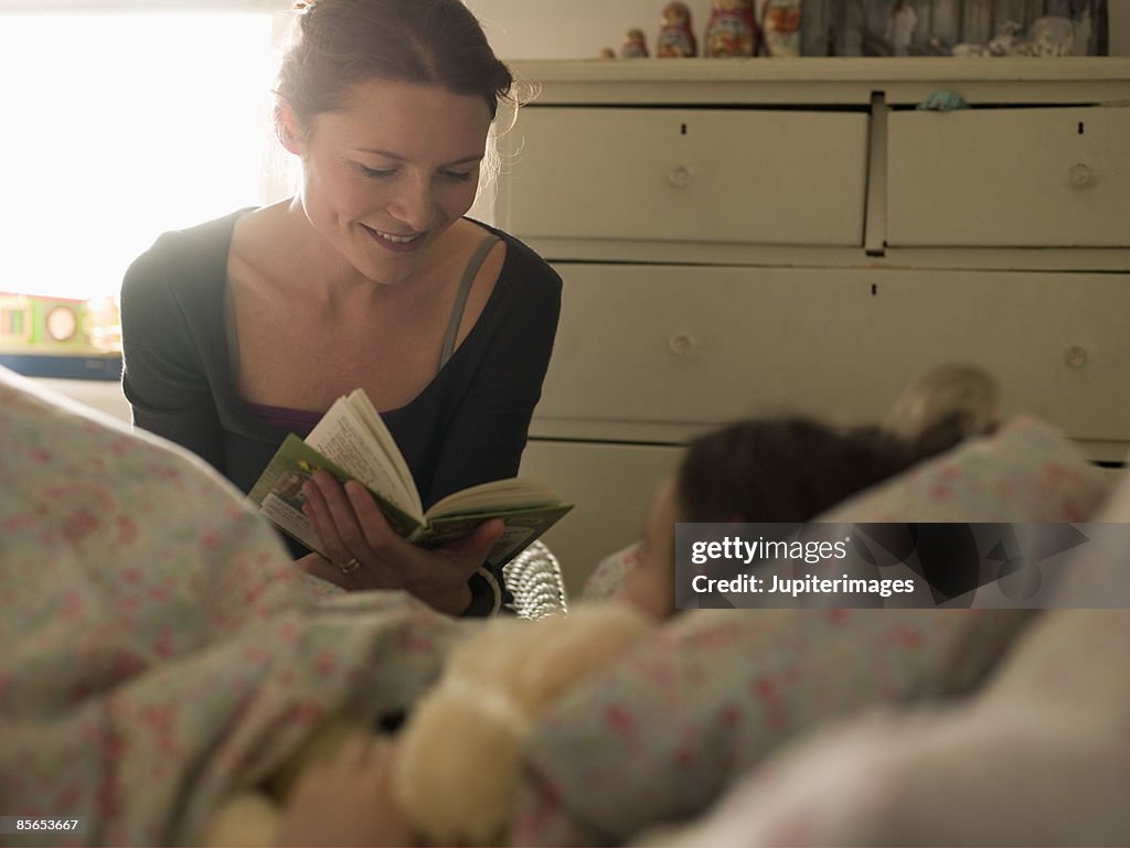 Woman reading to daughter in bed