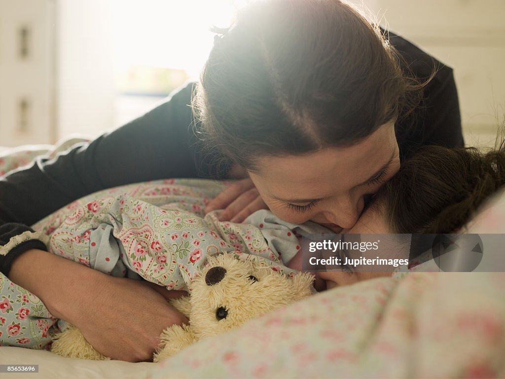 Affectionate mother with daughter in bed