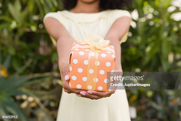 woman holding present - dar fotografías e imágenes de stock
