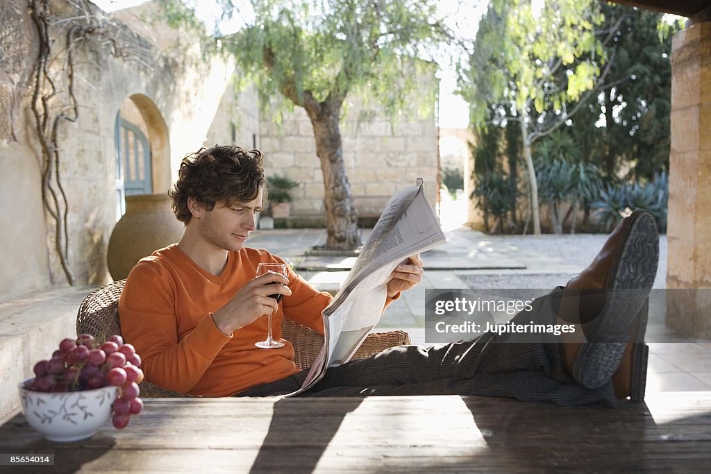 Man with newspaper and red wine