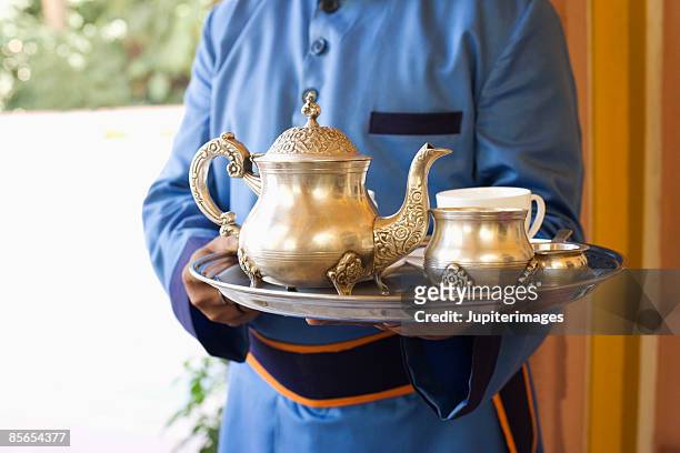butler holding silver tea service - indian subcontinent ethnicity stockfoto's en -beelden