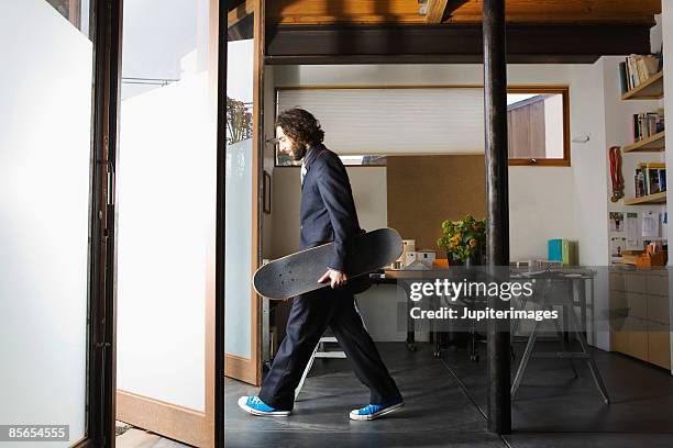 businessman exiting office holding skateboard - mischief stock pictures, royalty-free photos & images