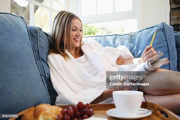 mid-adult woman doing crossword puzzle - kruiswoordpuzzel stockfoto's en -beelden