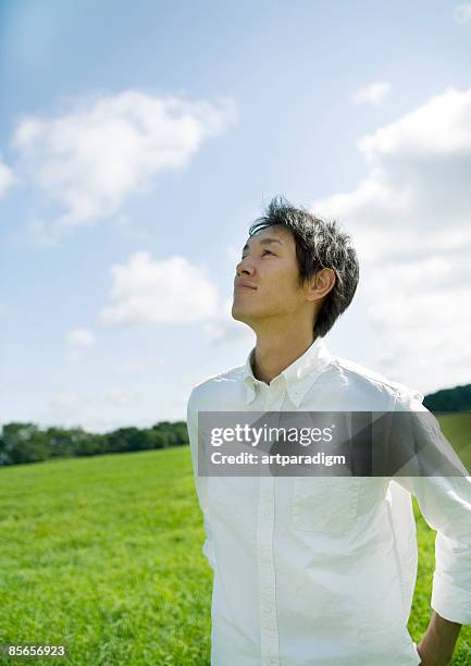 young man looking up blue sky - looking up ストックフォトと画像