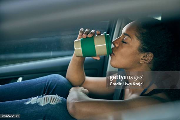 young woman waiting in car, drinking coffee - enjoying coffee stock pictures, royalty-free photos & images