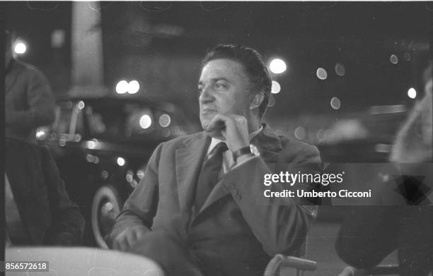 Italian film director Federico Fellini seats in a cafe in Via Veneto, Rome 1960. He is very relaxed and smiling.