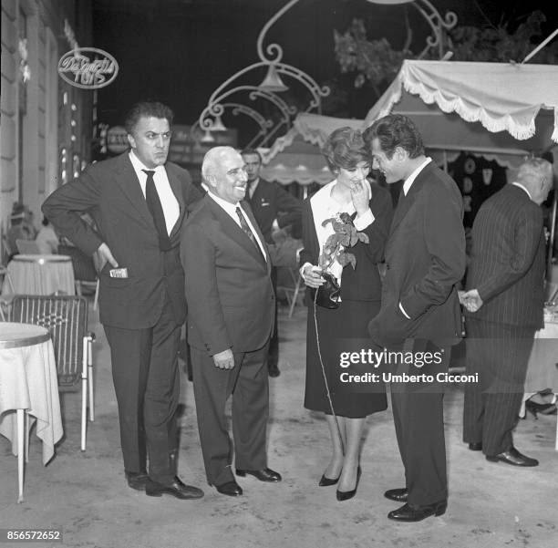 Italian film director Federico Fellini at the cocktail party for the movie 'La Dolce Vita' with film producer Angelo Rizzoli, actor Marcello...