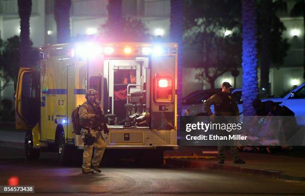 Las Vegas Metropolitan Police Department officers stand near an ambulance as medical personnel treat a person in the parking lot of the Hooters...