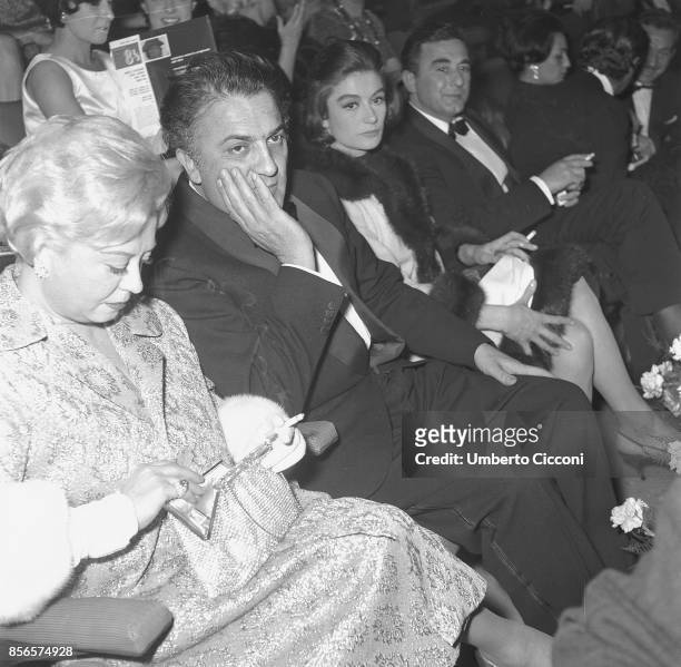 Italian film director Federico Fellini at the 'Cinema Fiamma' in Rome with Angelo Rizzoli , Giulietta Masina and Anouk Aimee.