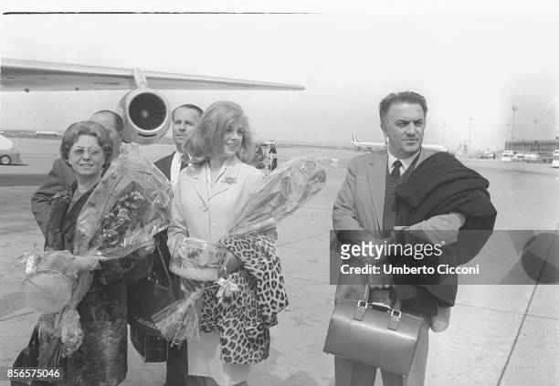 Italian film director Federico Fellini is at Fiumicino Airport with his wife and actress Giulietta Masina and the actress Sandra Milo leaving for...