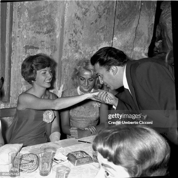 Italian film director Federico Fellini kisses the hand of actress Carla Del Poggio. Carla del Poggio is with Anna Salvatore.