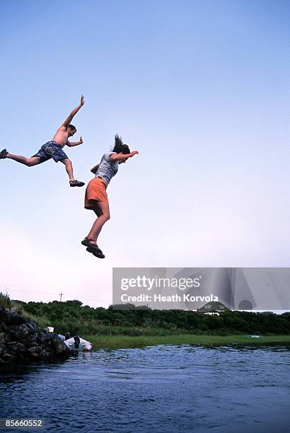 two people jumping off bridge into water. - rhode island bridge stock pictures, royalty-free photos & images