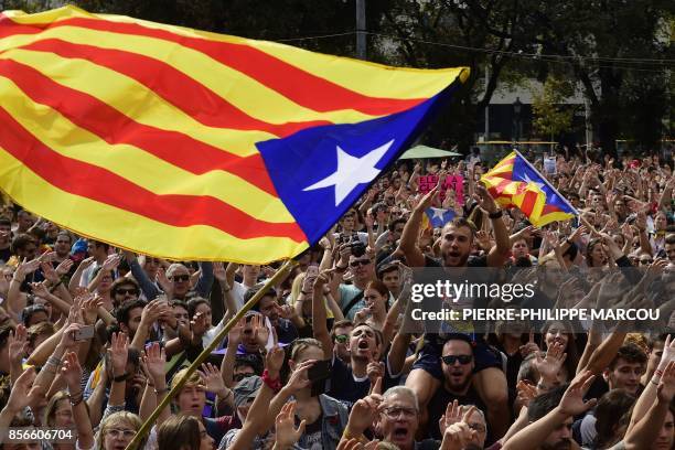 People shout slogans as they wave Catalan pro-independence 'Estelada' flags during a protest in Barcelona on October 2, 2017 a day after hundreds...