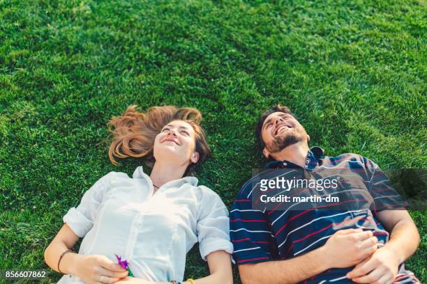 glückliches paar in den rasen träumen - im gras liegen stock-fotos und bilder