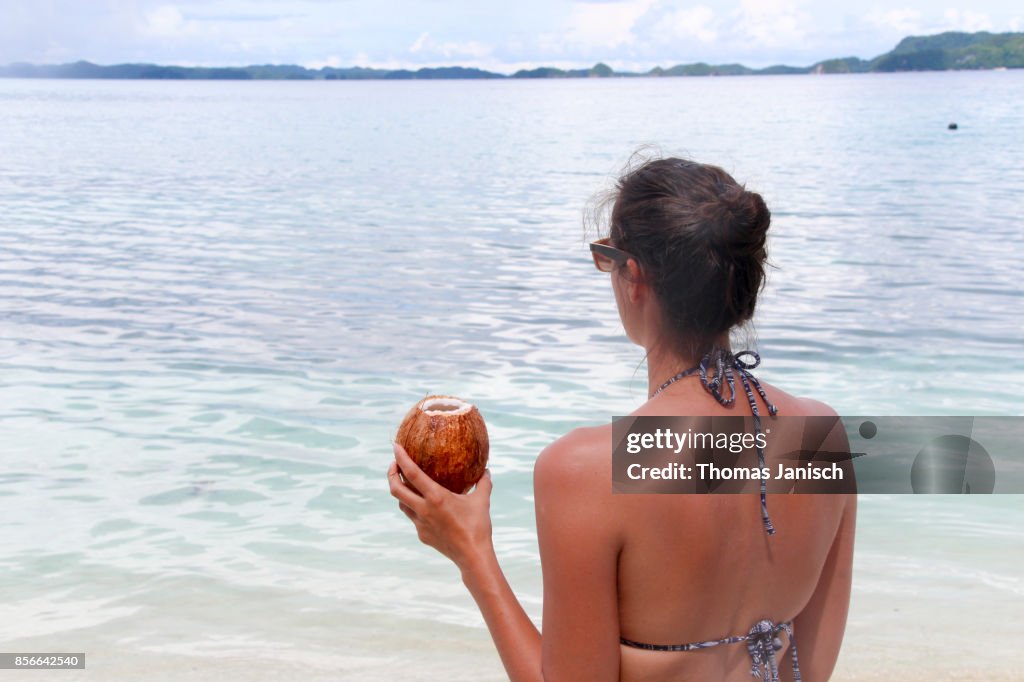 Woman looking into the distance with a coconut drink in the hand, Palau