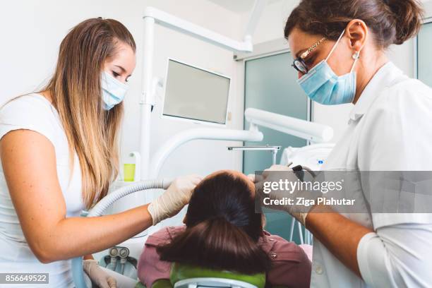 female dentist and her assistant at work - suction tube stock pictures, royalty-free photos & images