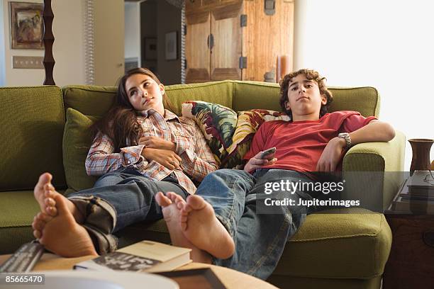 boy and girl sitting on sofa with remote control - boyfriend foto e immagini stock