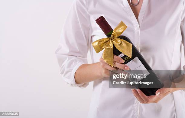 woman holding bottle of wine - wine gift stock pictures, royalty-free photos & images
