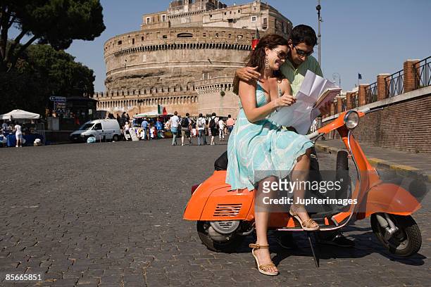 couple with map on motor scooter , saint angel castle , rome , italy - holiday scooter stock-fotos und bilder