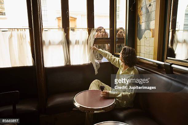 couple looking through cafe window - café paris stock pictures, royalty-free photos & images