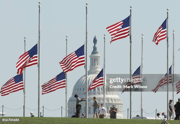Park Service employee lowers the U.S. Flags on the grounds of the Washington Monument to half-staff, on October 2, 2017 in Washington, DC. President...