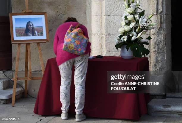 Woman writes a message of condolence next to a portrait of Mauranne in Eguilles, southern France, on October 2 the day after Mauranne and Laura, two...