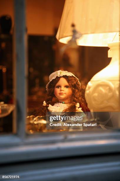 doll and a lamp seen through window at dusk - looking through a doll house photos et images de collection