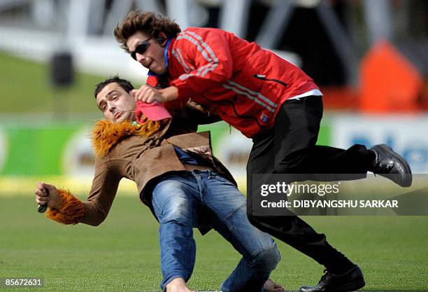 New Zealand security officer tackles a pitch invader to the ground during the third day of the second Test match at the McLean Park in Napier on...