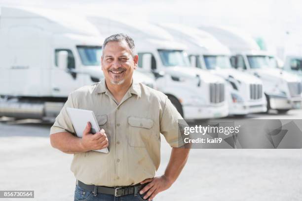 hispanic man standing in front of semi-trucks - man hand on hip stock pictures, royalty-free photos & images