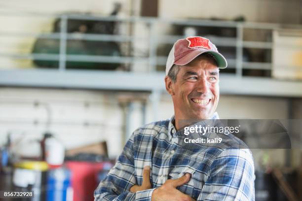 worker in garage wearing trucker's hat - man wearing baseball cap stock pictures, royalty-free photos & images