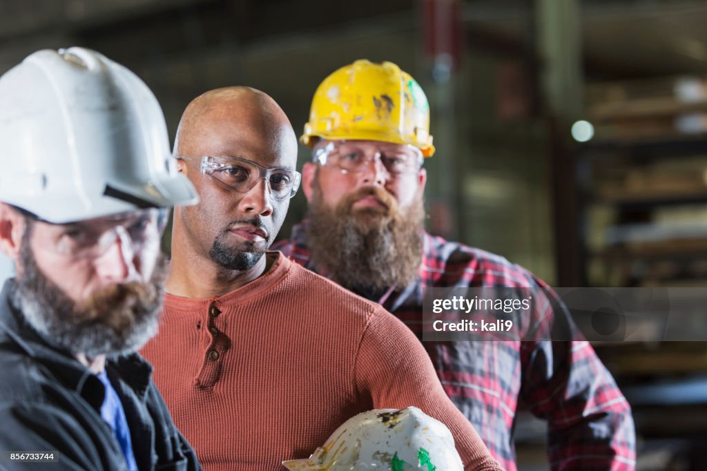 Tre allvarliga multietniska byggnadsarbetare